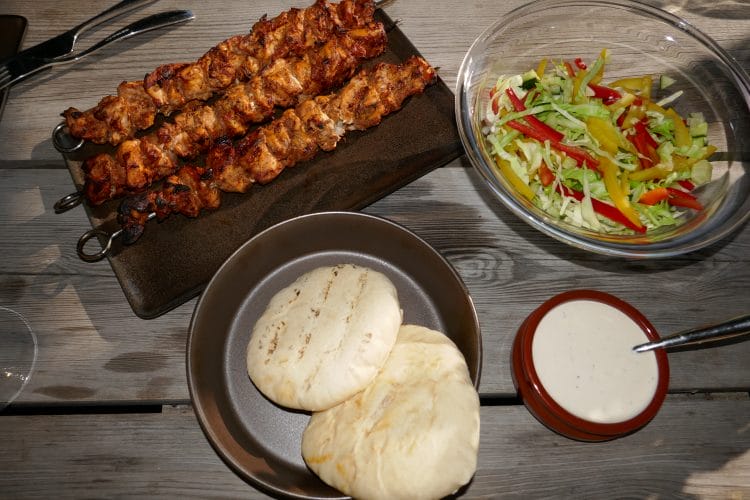 Grilled skewers with salad and garlic dressing in pita